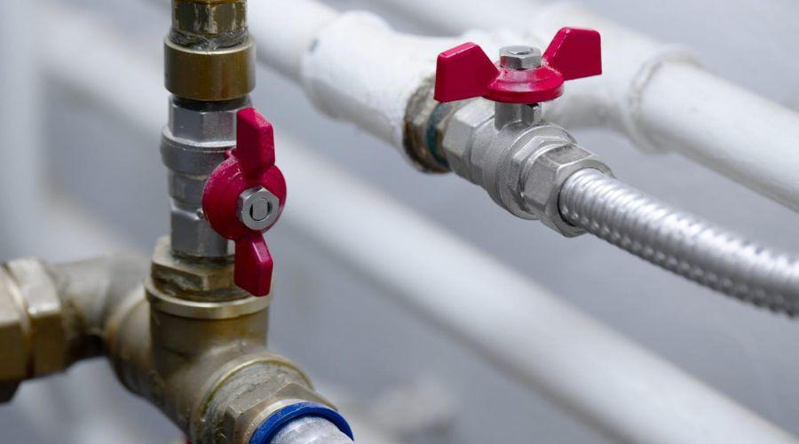 Image of plumbing valves and pipes showcasing metal fittings and red handles for Gray Plumbing Inc's installation services.